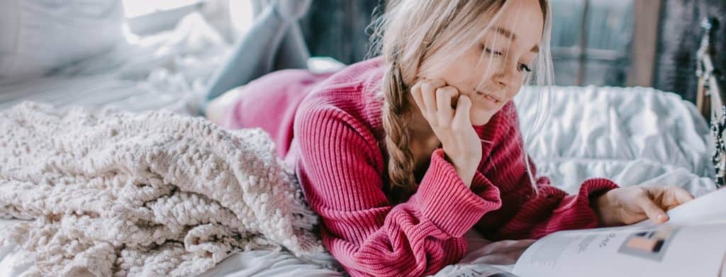 woman-looking-after-wellbeing-reading-on-bed
