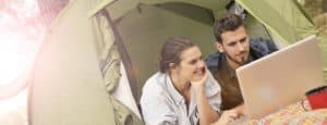 Happy-couple-using-laptop-in-tent