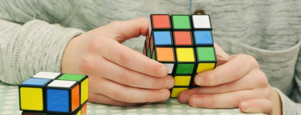 person trying to solve rubiks cub puzzle