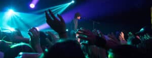 Man-Singing-on-Stage-With-Stage-Lights-Near-Crowd
