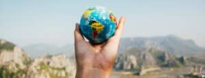 Person-Holding-World-Globe-Facing-Mountain
